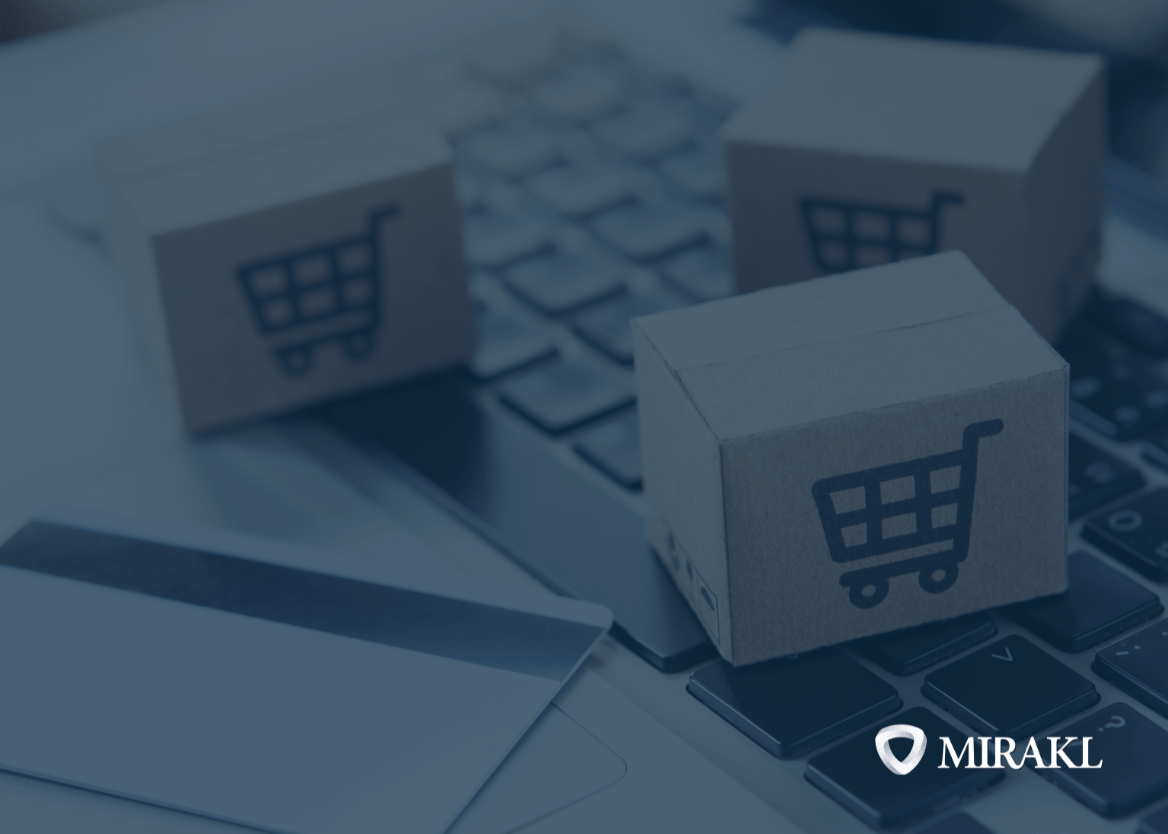 A close-up shot of three small cardboard boxes with printed shopping cart icons, arranged on a laptop keyboard. A credit card is partially visible in the bottom left. The Mirakl logo is in the bottom right corner, suggesting an eCommerce, marketplace or dropship context.
