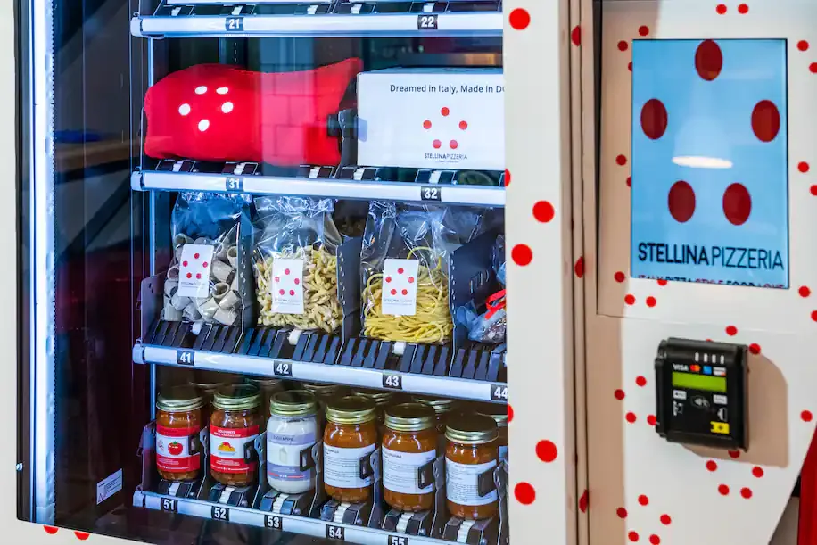 Stellina Pizzeria branded vending machine stocked with fresh pasta varieties and jarred sauces, with a payment terminal on the side