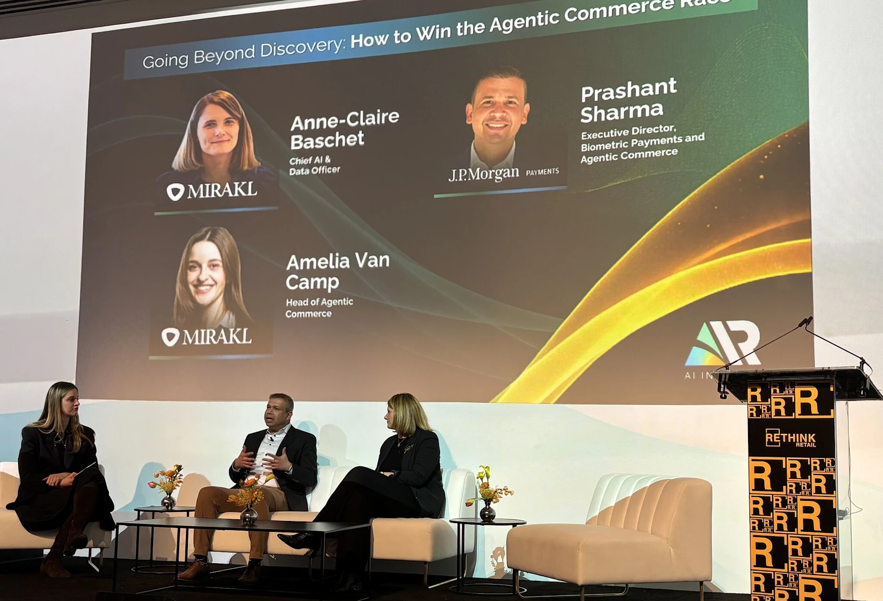 Panel discussion at the AiR Summit at NRF 2026 titled "Going Beyond Discovery: How to Win the Agentic Commerce Race." Three speakers on stage: Anne-Claire Baschet (Mirakl Chief AI & Data Officer), Prashant Sharma (J.P. Morgan, Executive Director, Biometric Payments and Agentic Commerce), and Amelia Van Camp (Mirakl Head of Agentic Commerce).