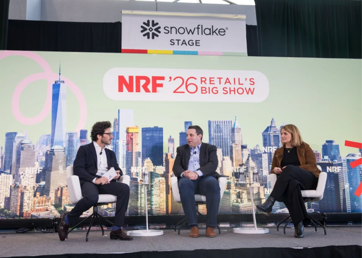 Three panelists in conversation on the Snowflake Stage at NRF '26 Retail's Big Show in New York City, seated in front of a large backdrop showing the NRF '26 logo against a Manhattan skyline.