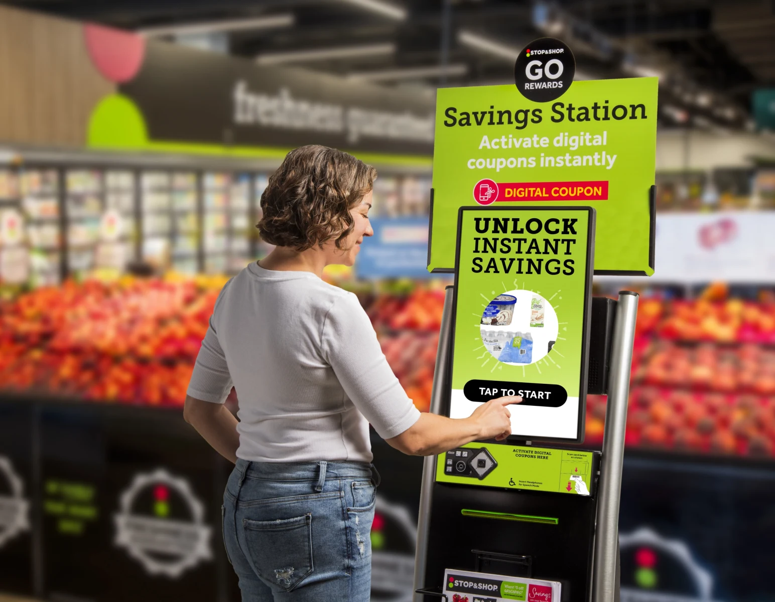A shopper uses a Stop & Shop Go Rewards "Savings Station" self-service kiosk inside a grocery store to activate digital coupons for instant savings.